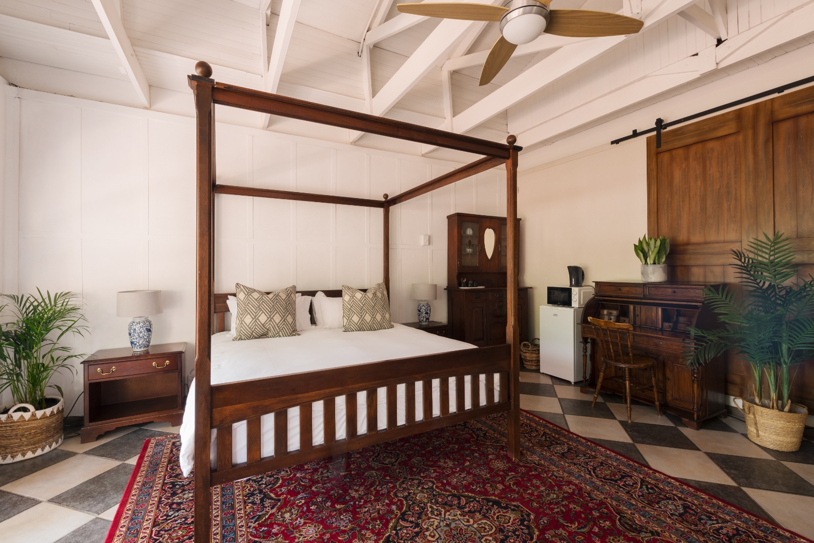 Deluxe King Room with four-poster bed and checkerboard floor at House Falcon Guest House Pretoria